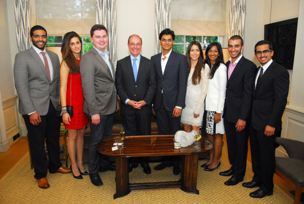 Group of seven people standing in a room, dressed formally.
